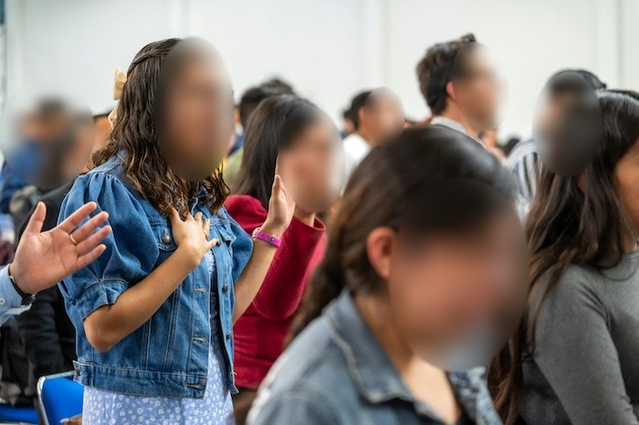 Believers worshiping at a church gathering (faces blurred)